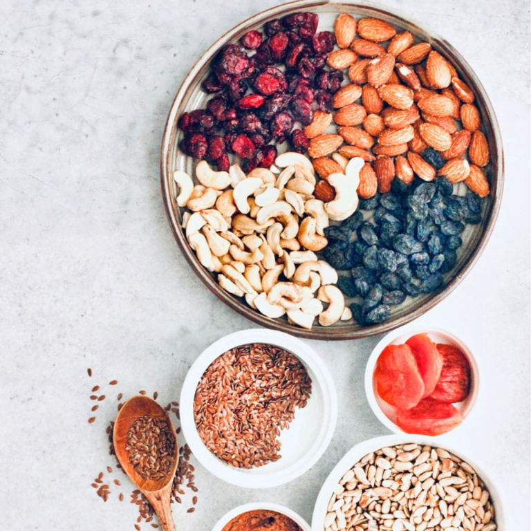 high fiber foods, berries and fruit on the plate , some seeds in the bowls on the sideand a wooden spoon, gray background